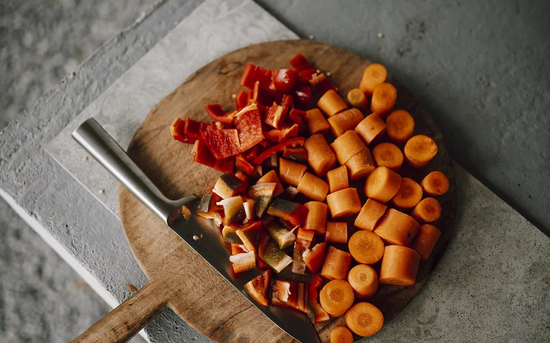Verdura picada y cuchillo sobre tabla redonda